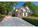 Well-maintained two-story home with a long driveway leading to an attached garage and manicured landscaping at 235 South St, Buford, GA 30518