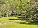 A lovely brick home with dormer windows is nestled among trees and a long driveway over a green lawn at 999 Grassdale Rd, Cartersville, GA 30121