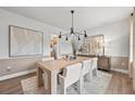 Modern dining room featuring a light wood table, white chairs, and contemporary lighting fixtures at 6100 Marigold Way, Atlanta, GA 30349