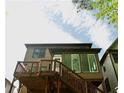 Back exterior view of home with stairs leading up to a deck, large windowed porch, and green siding at 5122 Micaela Way, Duluth, GA 30096