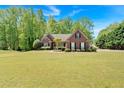 Well-kept brick home with a lush front yard, accented by mature trees and dark window shutters at 4309 Milford Pl, Hoschton, GA 30548