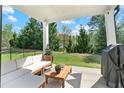 Inviting covered patio with outdoor seating, a grill, and a view of the lush backyard at 6070 Arbor Green Cir, Sugar Hill, GA 30518
