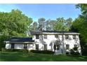 Inviting two-story white brick home featuring a dark roof, shuttered windows, and lush green surroundings at 3562 Sunderland Ne Cir, Atlanta, GA 30319