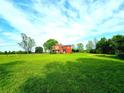 Wide view of a two-story home with beautiful blue sky, lush green lawn, and mature trees offering privacy at 68 Riveree Rd, Brooks, GA 30205