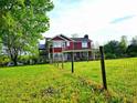 Two-story home with second-story deck and covered front porch surrounded by lush green lawn with wood fencing at 68 Riveree Rd, Brooks, GA 30205