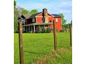Charming two-story home with stone chimney is surrounded by lush green lawn and mature trees, with wood fencing at 68 Riveree Rd, Brooks, GA 30205