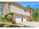 Two-car garage with brick and vinyl siding, accented by lush landscaping at 9082 Chestnut Lake Dr, Jonesboro, GA 30236