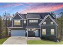 Two-story home featuring neutral siding, a dark roof, white trim, and an attached two-car garage under colorful sky at 3180 Tackett Rd, Douglasville, GA 30135