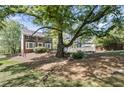 Spacious backyard featuring a mature tree with surrounding landscape and a two-story brick home at 510 Birch Ridge Ct, Roswell, GA 30076