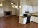 Open living room and kitchen area with a brick fireplace, modern appliances, and wood-look flooring at 6334 Forester Way, Lithonia, GA 30038