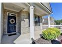 Inviting front porch with brick facade, decorative wreath on the door, and manicured landscaping at 5749 Creek Indian Dr, Sugar Hill, GA 30518
