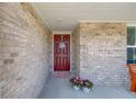 Close-up of a charming front door framed by brick, flower pots, and a welcoming wreath in a covered entryway at 6550 Lantana Village Way, Cumming, GA 30028