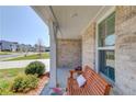 Inviting front porch with a wooden bench, white pillars, and lush landscaping; perfect for relaxing outdoors at 6550 Lantana Village Way, Cumming, GA 30028