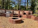 Outdoor cooking and entertainment area featuring a built-in grill, pizza oven, and a stone fire pit at 7027 Grinder Drive, Austell, GA 30168