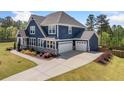 Beautiful home featuring a three-car garage, long drive, manicured lawn, stone accents, and attractive landscaping at 2111 Harmony Dr, Canton, GA 30115