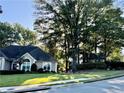 Lush front yard with mature trees frames this inviting home's exterior at 10825 Pinewalk Forest Cir, Alpharetta, GA 30022