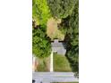 Bird's-eye view of a home's roof, driveway, and yard surrounded by mature trees and a street at 530 Bell Se Rd, Conyers, GA 30094