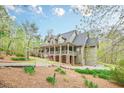 Home featuring a covered porch, dormer windows, stone accents, lush green landscaping, and an attached three-car garage at 18 Crolley Ln, White, GA 30184