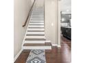 View of a staircase with hardwood treads, white risers, and a decorative carpet runner at 7691 Cabrini Pl, Fairburn, GA 30213