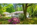 Well-kept white home with lush greenery, mature trees, and vibrant pink azaleas in a charming yard at 754 Pinehill Se Dr, Smyrna, GA 30080