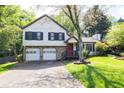 Charming two-story home featuring a stone facade, red door, two-car garage and a well-manicured lawn and mature trees at 1763 Hearthstone Cir, Lawrenceville, GA 30043