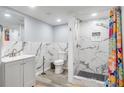 Modern bathroom featuring a walk-in shower with marble-look tiles, a gray vanity, and colorful shower curtain at 2162 Doris Dr, Decatur, GA 30034