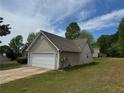 Residential home with an attached two-car garage, vinyl siding, and a paved driveway on a grassy lot at 10111 Commons Way, Jonesboro, GA 30238