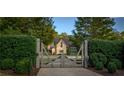 View of the front gate with a glimpse of the stone home in the distance, framed by lush greenery and mature trees at 2979 Ridgewood Nw Rd, Atlanta, GA 30327