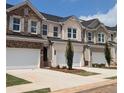 Row of townhouses featuring brick and siding exteriors, two-car garages, and meticulously landscaped front yards at 877 Pensive Run, Dacula, GA 30019