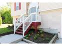 Inviting front porch featuring white railings, red stairs, and a landscaped garden bed at 140 Maplewood Dr, Temple, GA 30179