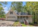 Charming two-story home with a front porch, attached garage, and mature trees on a sunny day at 365 Falling Timber Ct, Stockbridge, GA 30281