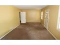Spacious living room with yellow walls, carpeted floors, and natural light from multiple windows at 811 Verde Dr, Riverdale, GA 30274
