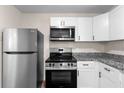 Modern kitchen featuring stainless steel appliances, granite countertops, and white cabinets at 6703 Cameron Rd, Morrow, GA 30260