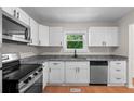 Modern kitchen featuring stainless steel appliances, granite countertops, and white cabinets at 6703 Cameron Rd, Morrow, GA 30260