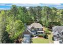 A lovely home surrounded by mature trees boasts a manicured lawn and charming curb appeal in this aerial view at 3918 Windgrove Xing, Suwanee, GA 30024