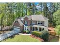 Beautiful two-story brick home with attached garage and manicured front lawn in a serene, wooded setting at 3918 Windgrove Xing, Suwanee, GA 30024
