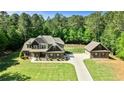 Stunning aerial view of a brick home with detached garage, long driveway, and lush greenery at 105 Chantilly Ln, Fayetteville, GA 30215