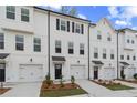 Modern townhome row featuring crisp white exteriors, black trimmed windows, and individual single-car garages at 3170 Washburn Sw St, Atlanta, GA 30354