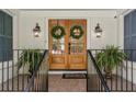 A welcoming front porch with a brick facade, wood double doors, and decorative green wreaths at 5641 Roberts Dr, Dunwoody, GA 30338