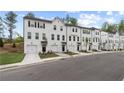 Modern white townhomes with garages, black trim, landscaping, and sidewalks at 148 Werner Brook Sw Way, Atlanta, GA 30354