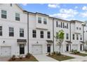 Elegant townhouses featuring white siding, black doors, attached garages, and manicured front lawns at 148 Werner Brook Sw Way, Atlanta, GA 30354