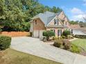 Brick home featuring a two-car garage, spacious driveway, and beautiful landscaping with trees and shrubs at 374 Meadowmeade Cv, Lawrenceville, GA 30043