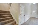 Bright foyer with carpeted staircase, and paneled walls leading to front door at 119 Felicity Pike, Locust Grove, GA 30248