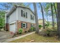 Home with a brick and gray exterior featuring an attached garage and mature trees surrounding the property at 1292 Marcelle Heights Nw Pl, Norcross, GA 30093