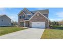 New two story brick home featuring a two car garage, well manicured lawn, and classic architectural design at 115 Felicity Pike, Locust Grove, GA 30248