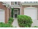 Home's inviting entryway features a dark front door, lush green bushes and brick accents at 1491 Bellsmith Dr, Alpharetta, GA 30076