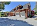 Spacious brick home featuring a three-car garage, a large driveway, and mature trees at 870 Longstone Lndg, Alpharetta, GA 30022