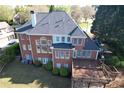 Expansive brick home featuring a large wooden deck, manicured lawn, and lush landscaping at 870 Longstone Lndg, Alpharetta, GA 30022