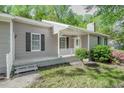 Close-up of the home's entrance, showcasing a covered porch with white lattice and a well-maintained lawn at 2374 Rolling Acres Sw Dr, Conyers, GA 30094
