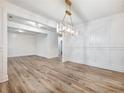 Dining area features wood floors, wainscoting, modern chandelier, and doorway access at 4201 Hosch Reserve Dr, Buford, GA 30519
